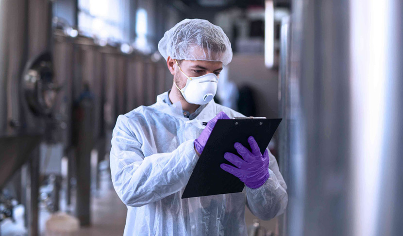 Lucrător în halat de protecție ia notiţe 