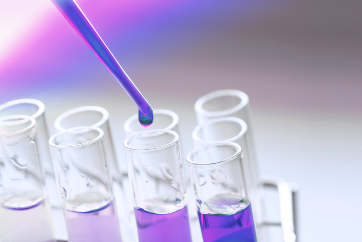 Pipetă care dozează lichid violet într-o eprubetă